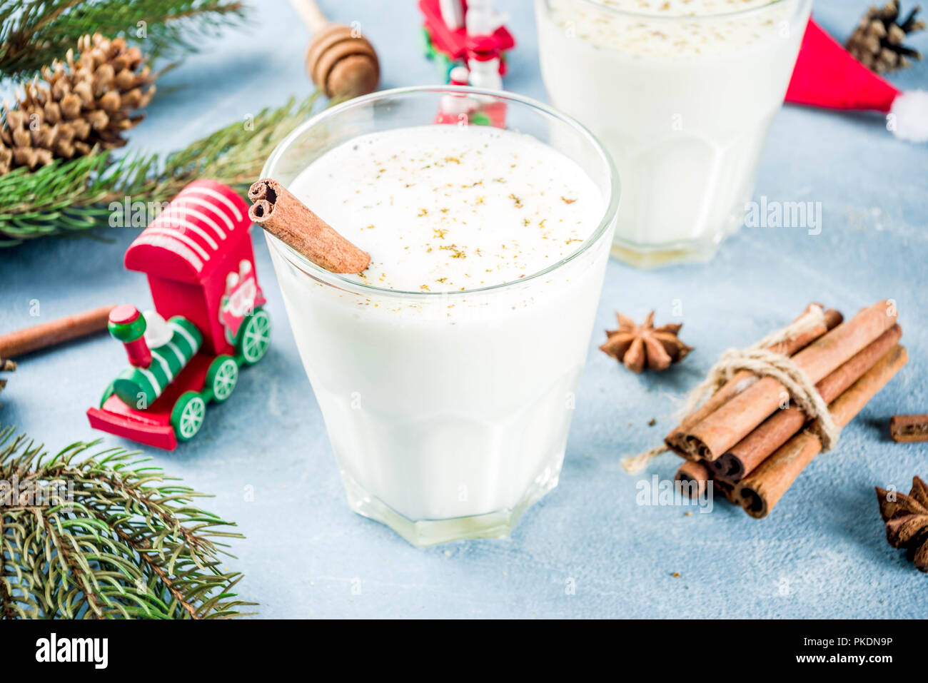 Traditional winter festive drink, sweet and spicy christmas eggnog cocktail in a glasses, on light blue background with xmas decorations, copy space. Stock Photo