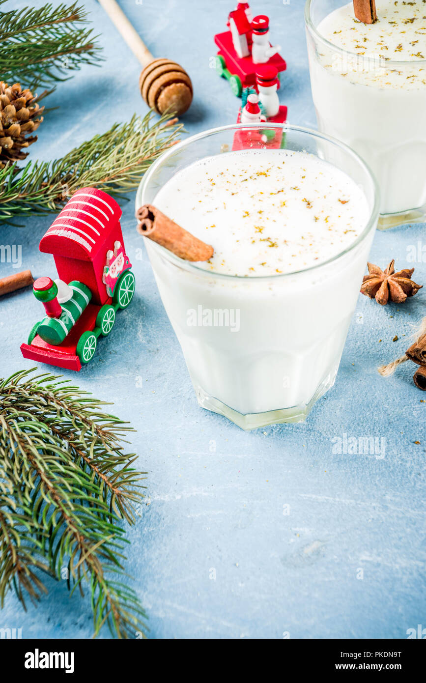 Traditional winter festive drink, sweet and spicy christmas eggnog cocktail in a glasses, on light blue background with xmas decorations, copy space. Stock Photo
