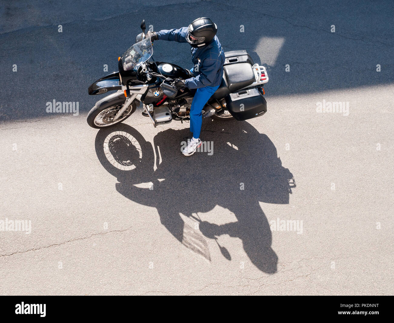 Overhead view of solo motorbike rider with shadow on road - France. Stock Photo