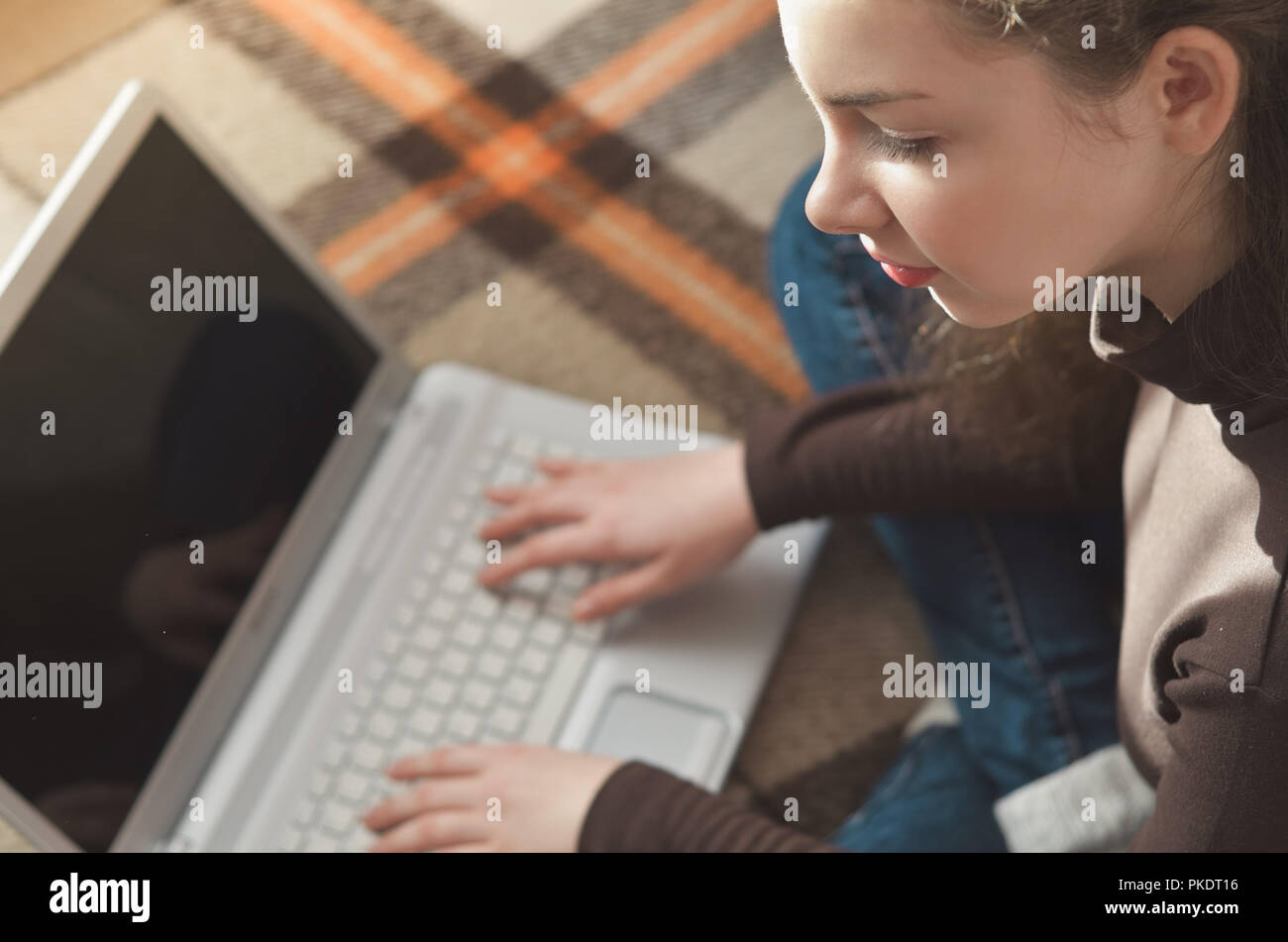 Top view of young teen girl couch prepares report on business lesson, corrects mistakes, keyboards on laptop computer, searches information. Student d Stock Photo