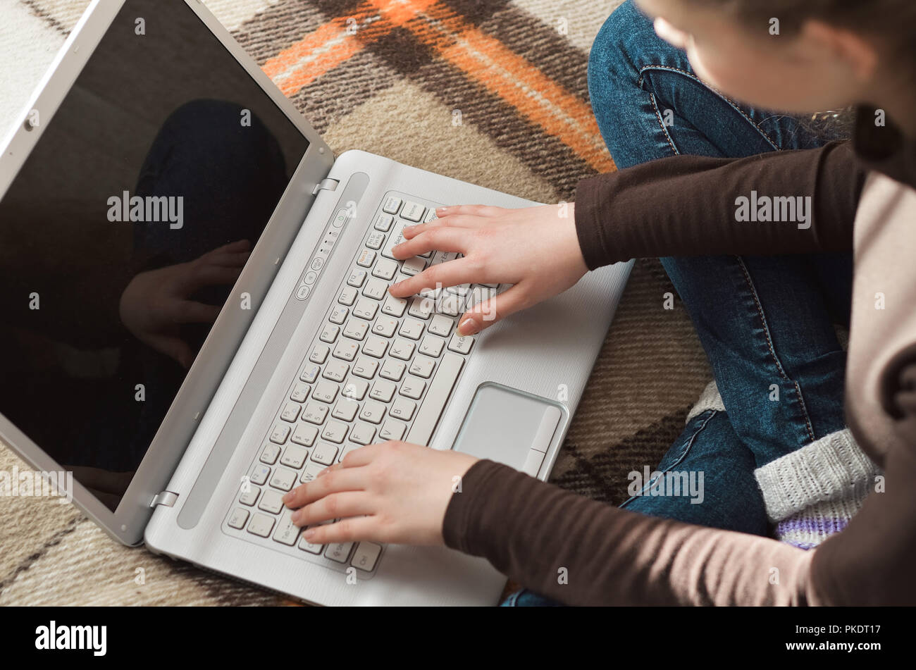 Top view of young teen girl couch prepares report on business lesson, corrects mistakes, keyboards on laptop computer, searches information. Student d Stock Photo