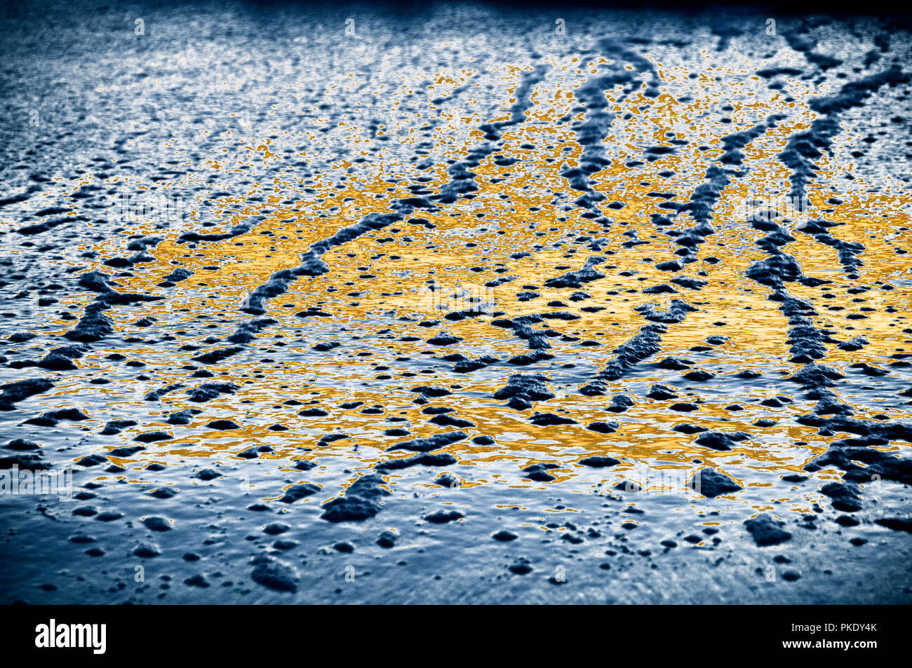 Receding wave ripples at low tide with bubbles and reflections of sunset and sky. Stock Photo