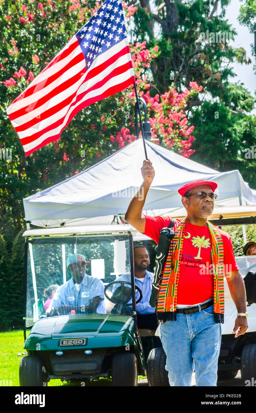 An African-American man carries an American flag during a protest outside the South Carolina State House, July 10, 2015, in Columbia, South Carolina. Stock Photo
