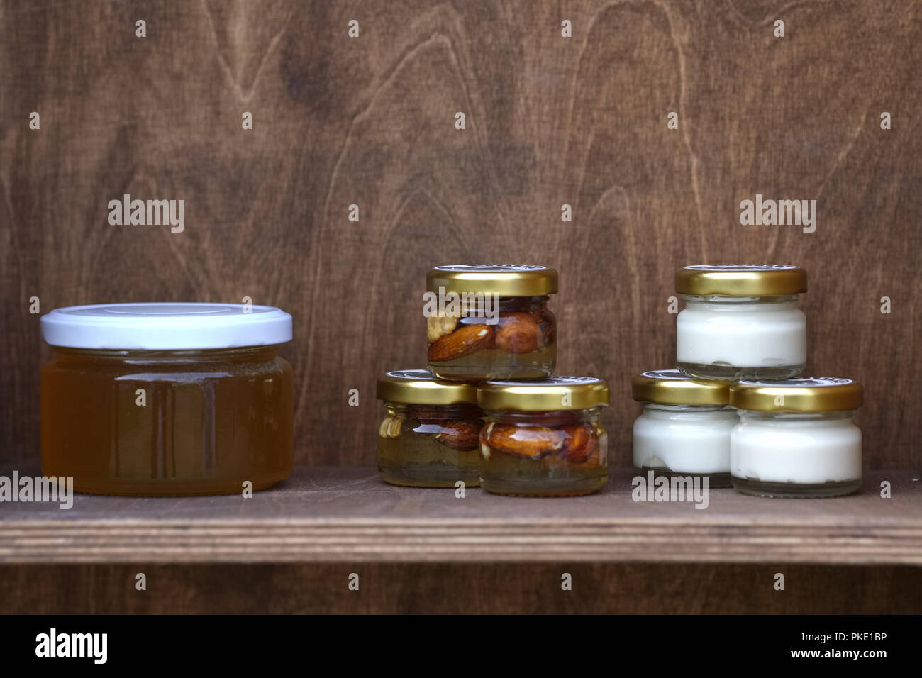 Nuts and honey in small jars on shelf Stock Photo