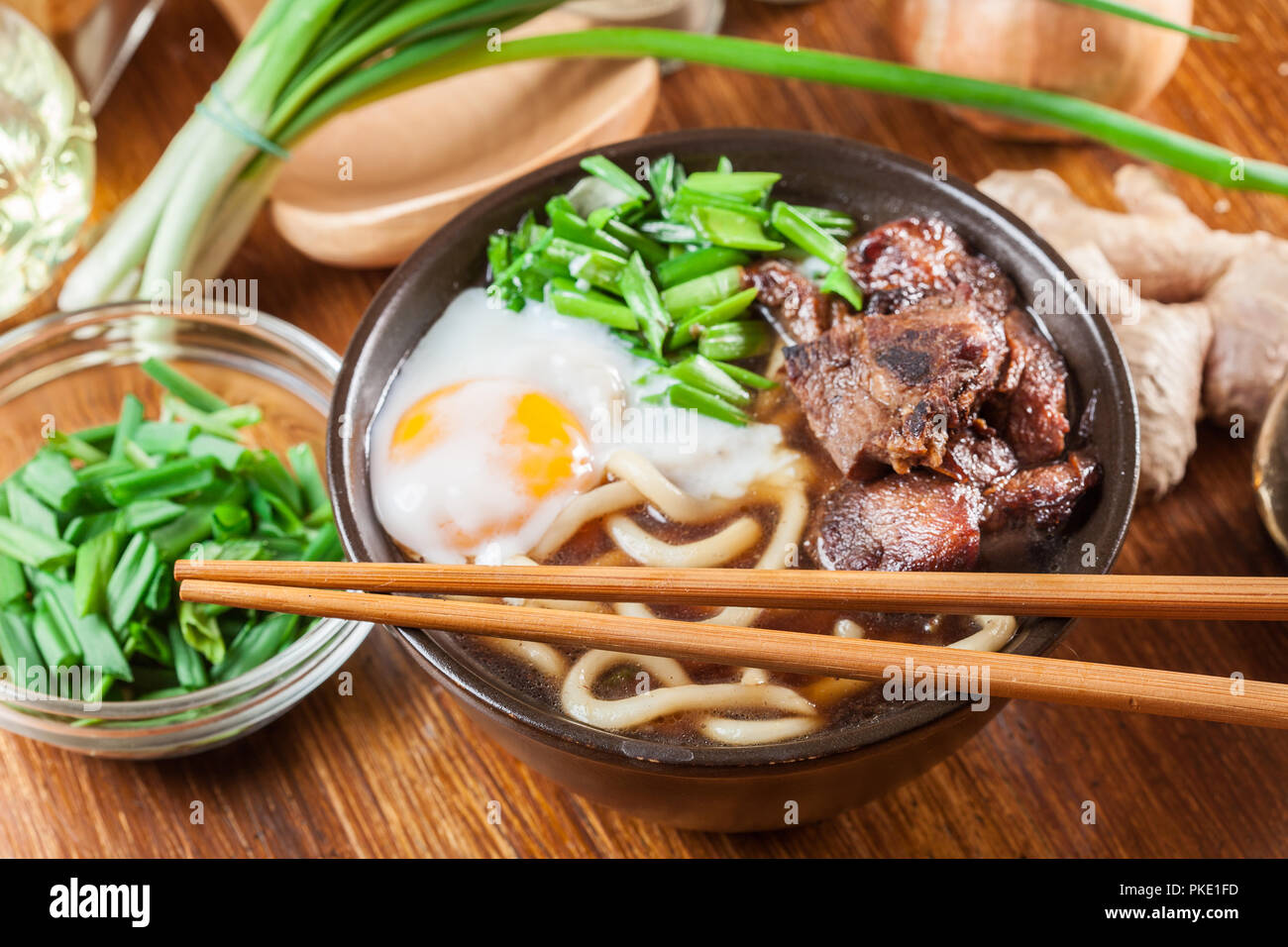 Japanese Udon noodles with beef, egg, green onion and soup in a brown