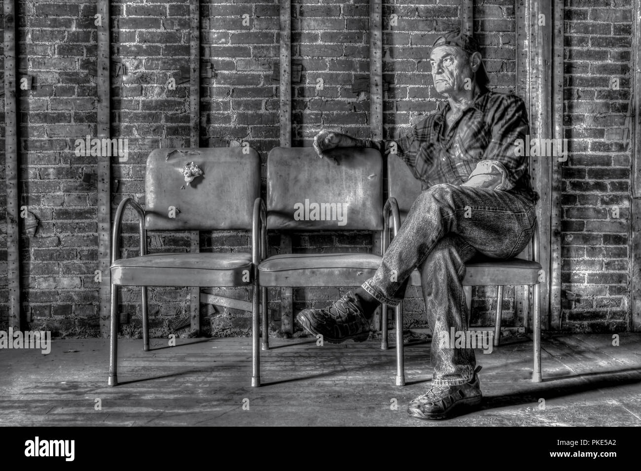Portrait of a tired middle-aged Caucasian man sitting on a row of old chairs. Stock Photo