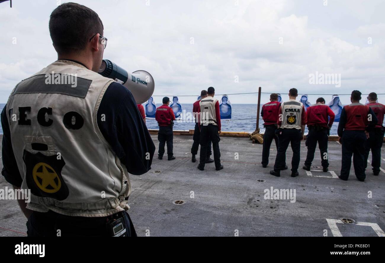 WATERS SOUTH OF JAPAN (July 29, 2018) Master-at-Arms 1st Class Ethan Acosta, from Castroville, Texas, instructs Sailors on the next course of fire during a small arms qualification aboard the Navy’s forward-deployed aircraft carrier, USS Ronald Reagan (CVN 76). Ronald Reagan, the flagship of Carrier Strike Group 5, provides a combat-ready force that protects and defends the collective maritime interests of its allies and partners in the Indo-Pacific region. Stock Photo