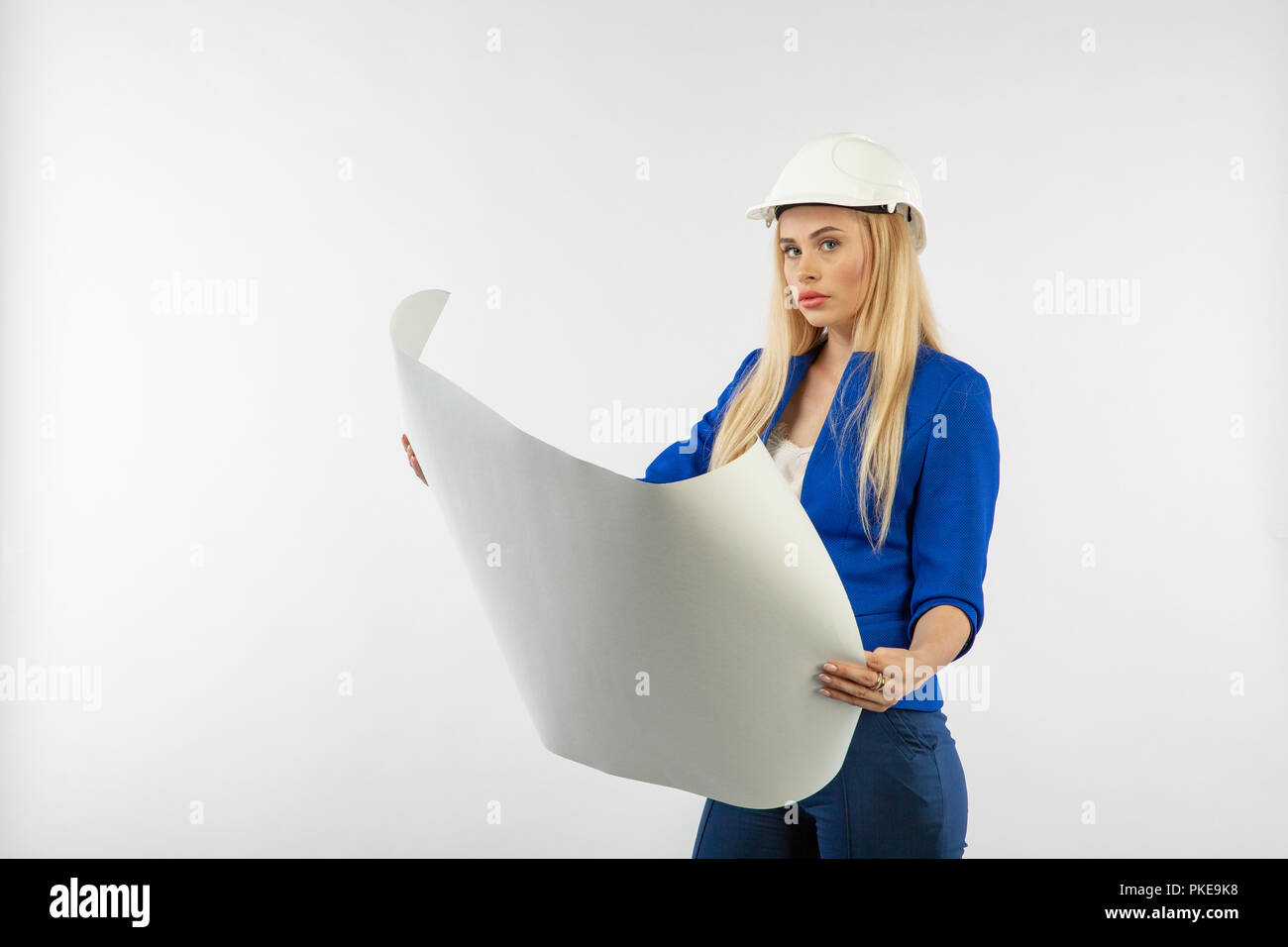 Employee woman in suit standing in helmet with paper documents on white ...