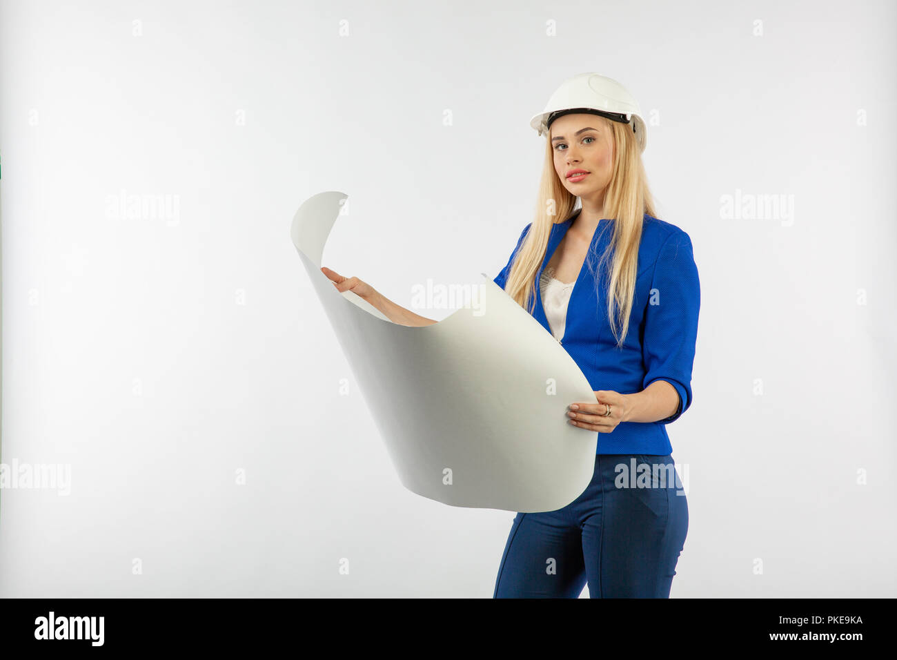 Employee woman in suit standing in helmet with paper documents on white ...