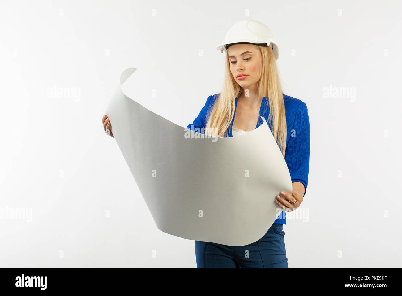 Employee woman in suit standing in helmet with paper documents on white ...