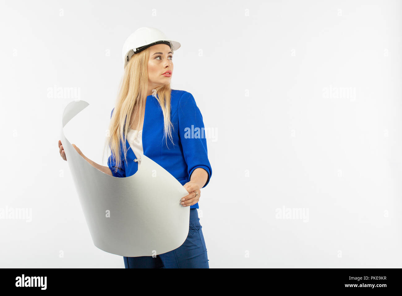 Employee woman in suit standing in helmet with paper documents on white ...