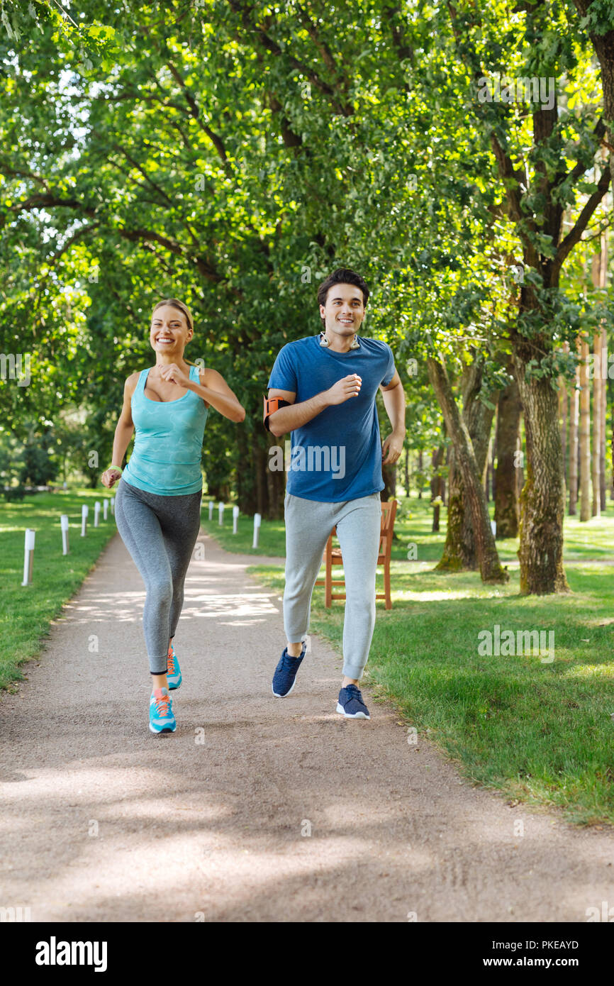 Nice positive young couple running outdoors together Stock Photo