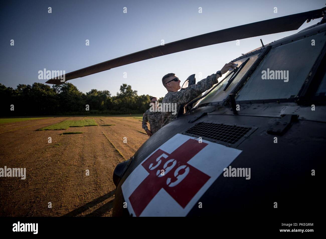 U.S. Army 1st Lt. Brandon Zakris, assigned to C Co., 1-171st GSAB (Medevac), Rochester, N.Y., prepares a UH-60 Blackhawk before competition jumps begin during Leapfest at the University of Rhode Island, West Kingston, R.I., Aug. 5, 2018. Leapfest is the largest, longest standing, international static line parachute training event and competition hosted by the 56th Troop Command, Rhode Island Army National Guard to promote high level technical and esprit de corps within the International Airborne community. Stock Photo