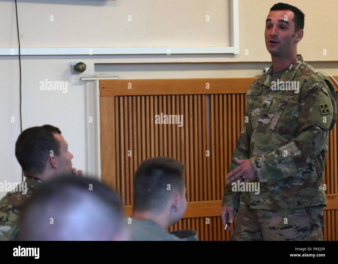 Staff Sgt. James Heroux, a chemical, biological, radiological and nuclear specialist with Headquarters and Support Company, 404th Aviation Support Battalion, 4th Combat Aviation Brigade, explains formulas meant to calculate the trajectory of a fired 5.56 mm round during his Master Marksmanship Course lecture in Illesheim Army Air Field, Germany, August 10, 2018. Heroux is one of the few small arms master gunners able to teach the MCC for 4th CAB, preparing Soldiers to quickly respond to threats and ensure support to European allies during Operation Atlantic Resolve. Stock Photo