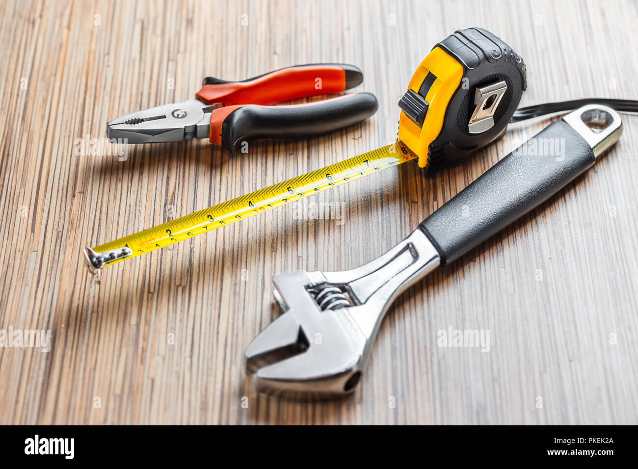 Adjustable pliers, Wrench and measuring tape on wooden table background