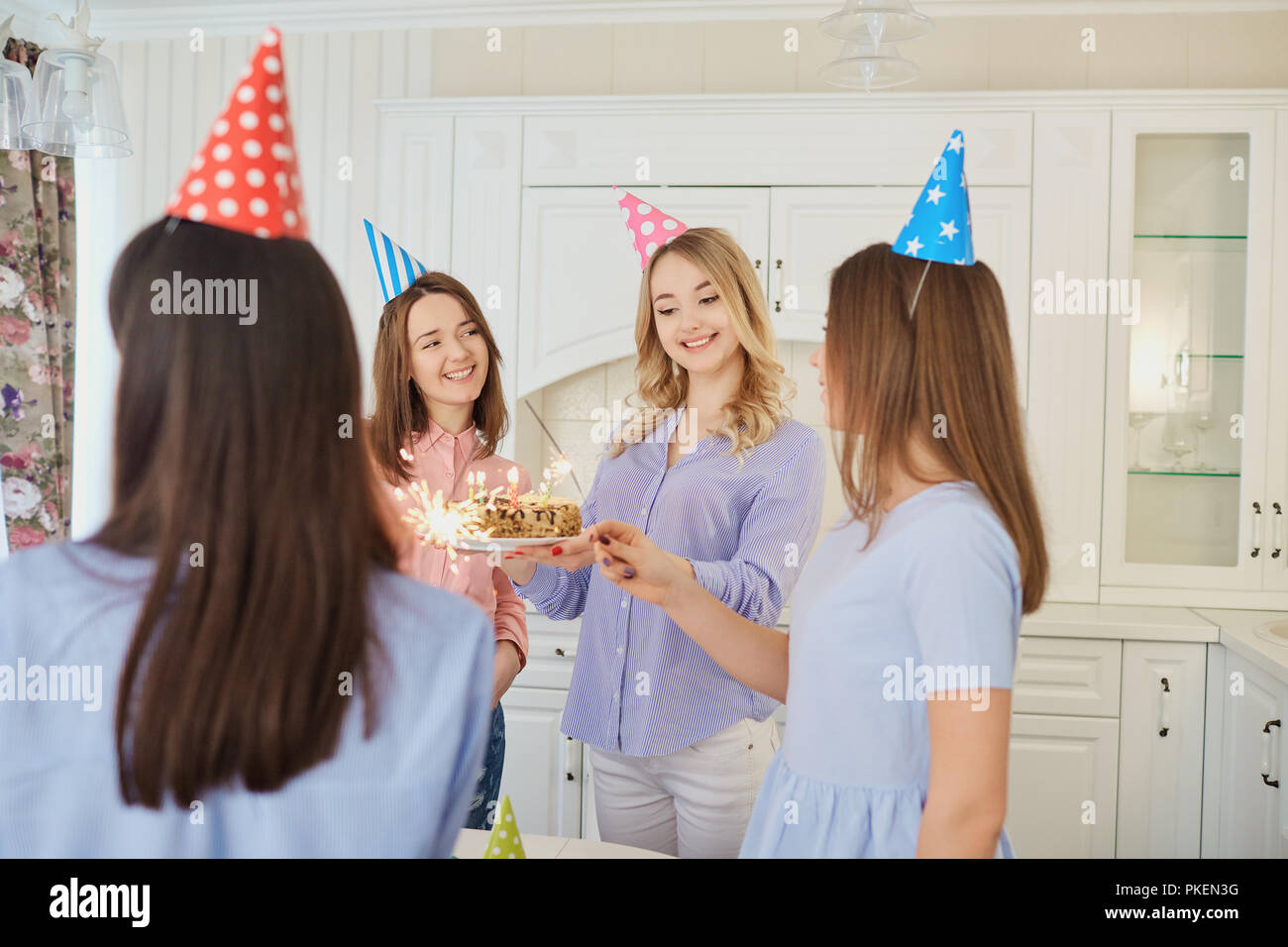 A group of girlfriends with a cake with candles celebrate a birt Stock Photo