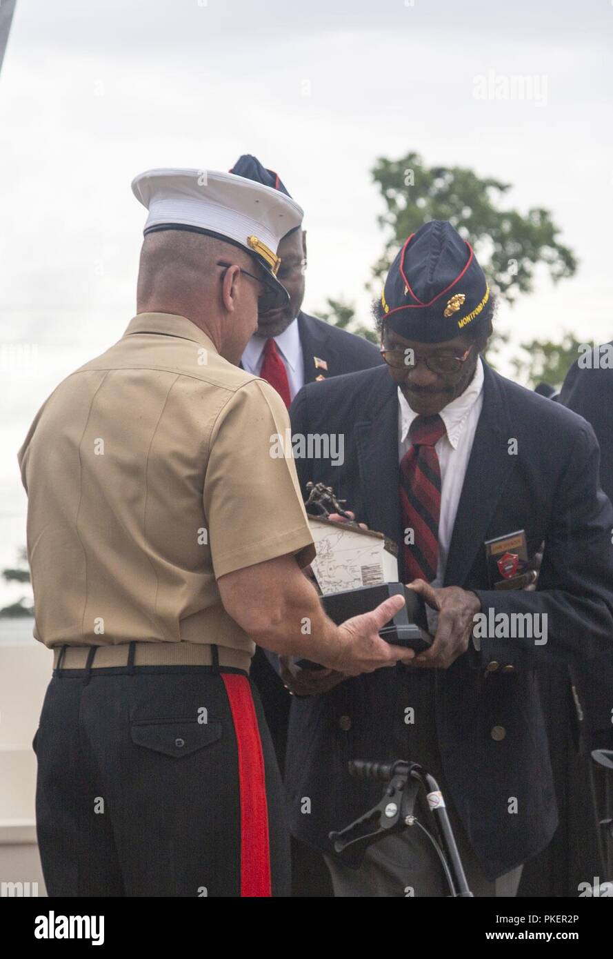 Former U.S. Marine Corps Sgt. John Spencer (right), presents Lt. Gen. Robert Hedelund, commanding general, II Marine Expeditionary Force, with a gift during the Montford Point Gifting Ceremony at Lejeune Memorial Garden in Jacksonville, N.C., July 25. The purpose of the ceremony was to officially transfer possession of the National Montford Point Marine Memorial to the Department of the Navy. Stock Photo