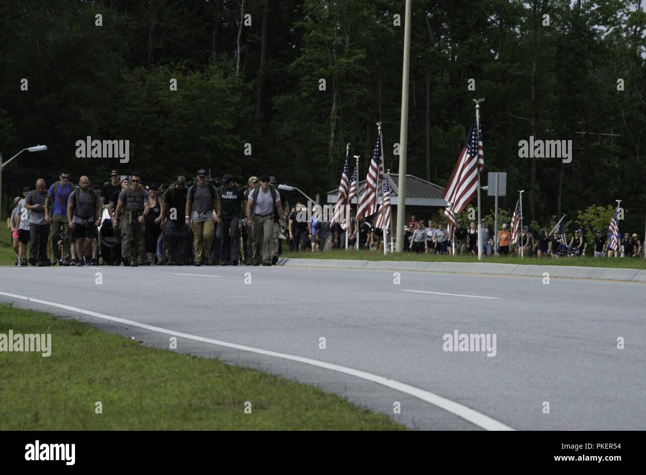 Service members and family and friends of the seven U.S. Marine Raiders and nine Marine Aviator crew members who died in the July, 2017, KC-130 crash in Laflore County, Miss., finish the last leg of their 900-mile memorial hike at Marine Corps Special Operations Command on Marine Corps Base Camp Lejeune, July 26. The hike started at the memorial site in Itta Bena, Mississippi, traveling 900-miles to Camp Lejeune. 10 teams took turns hiking a continuous 24 hours until reaching Stump Sound Park, but the final stretch finished at the MARSOC Compound on MCB Camp Lejeune. Stock Photo
