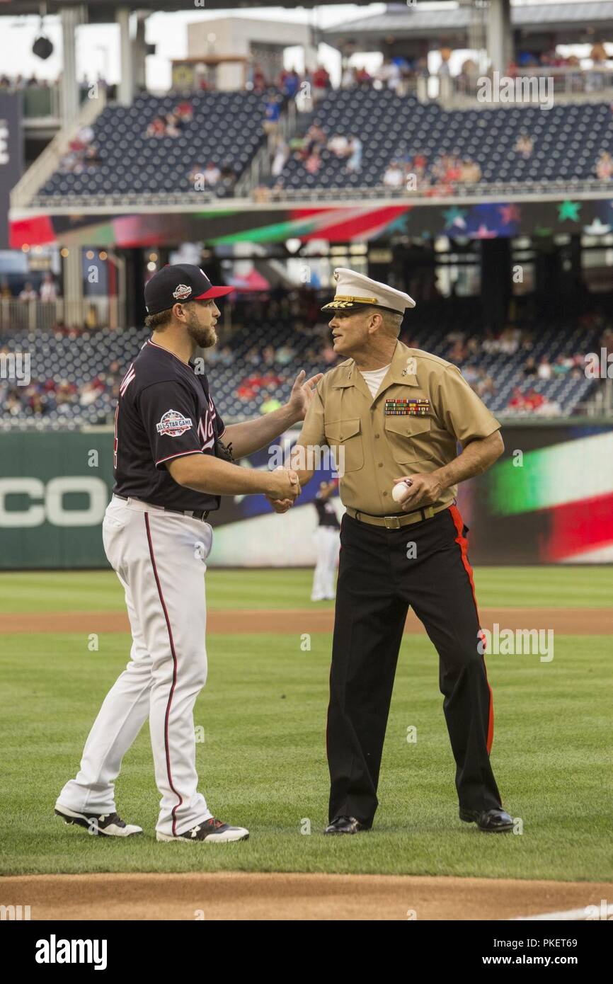 Major Gen. John R. Ewers Jr., staff judge advocate to the Commandant of the Marine Corps, shakes the hand of Washington Nationals catcher, Spencer Kieboom, during U.S. Marine Corps Day at Nationals Park, Washington D.C., July 31, 2018. The Washington Nationals hosted Marines stationed around the National Capital Region to participate in pre-game events to honor the Marine Corps. Stock Photo