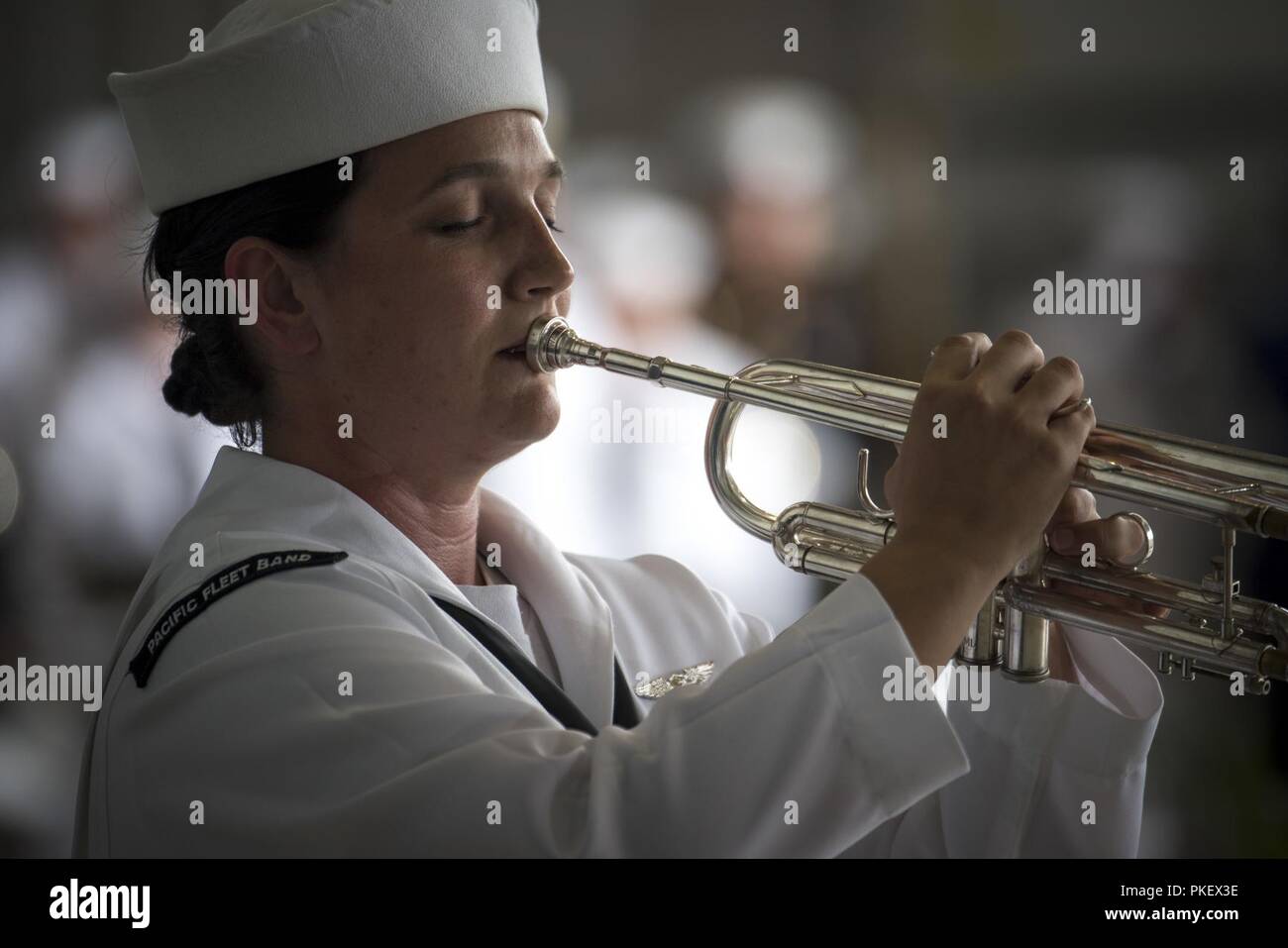 A member of the U.S. Pacific Fleet Band plays 'Taps' during an honorable carry ceremony at  Joint Base Pearl Harbor-Hickam (JBPH-H), Hawaii, Aug. 1, 2018. Attendees, to include Vice  President Mike Pence, U.S. Indo-Pacific Command Commander Navy Adm. Phil Davidson, Rear Adm. Jon Kreitz, Defense POW/MIA Accounting Agency deputy director, Korean War veterans and families of missing Korean and Vietnam troops, were on hand to watch the arrival of 55 flag-draped transfer cases containing what are believed to be the remains of American service members lost in the Korean War. Stock Photo