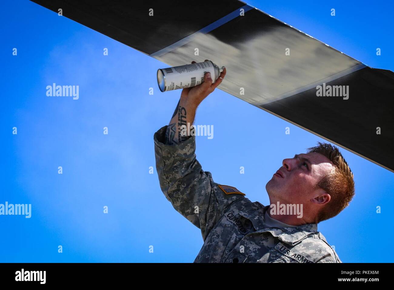 Spc. Christopher Cuddington, Charlie Company, 1st Battalion, 140th Aviation Regiment, sprays a white section on the blade of a UH-60 Black Hawk helicopter in preparation for wild fire support, July 31, 2018. The painted section will create a white disc so that the helicopter will be highly visible in the smoke and haze given off from forest fires. Stock Photo