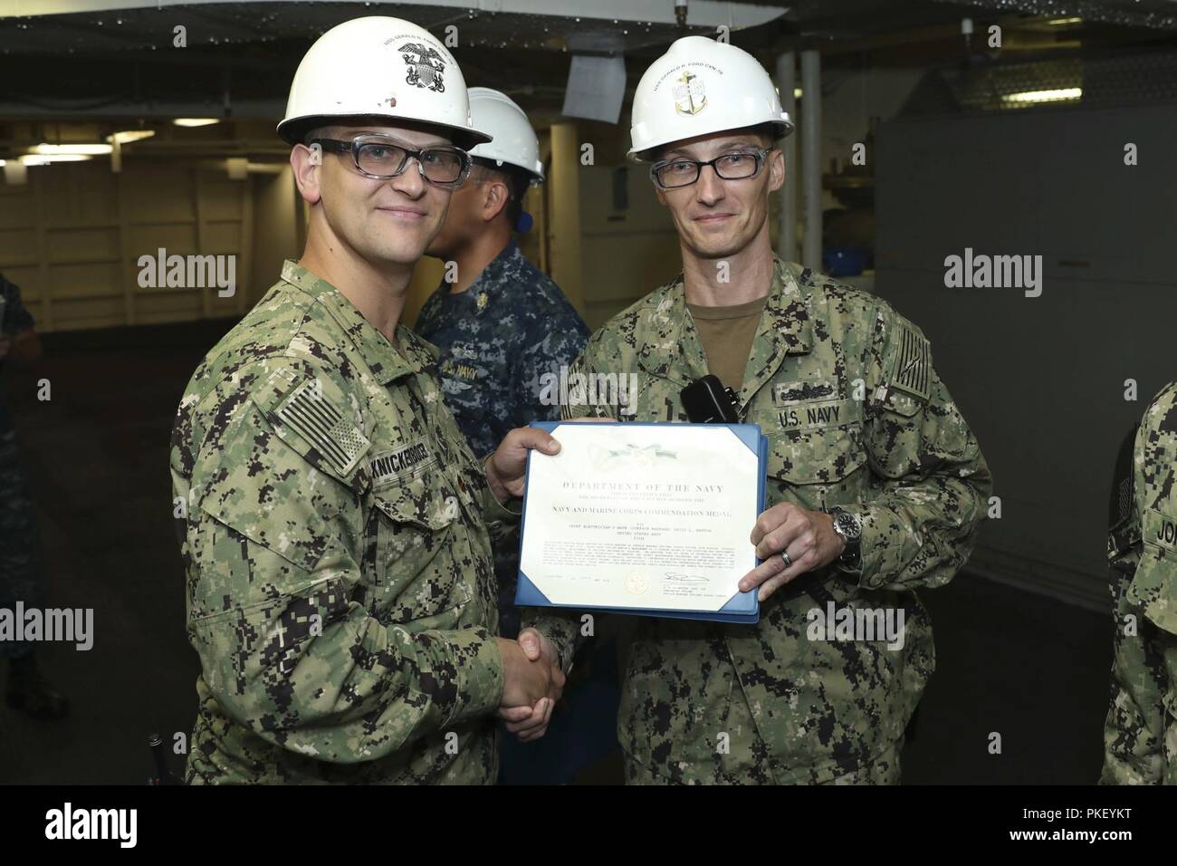NEWPORT NEWS, Va. (Aug. 2, 2018) Chief Electricians Mate David Newton, from Post Deposit, Maryland, assigned to USS Gerald R. Ford’s (CVN 78) engineering department, receives a Navy and Marine Corps Commendation Medal certificate from Lt. Cmdr. Michael Knickerbocker, Ford’s auxiliaries officer, during an awards ceremony on Ford. Stock Photo