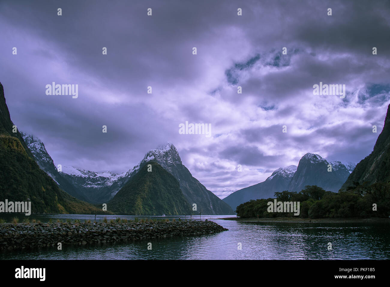 Milford Sound and Mitre Peak, South Island, New Zealand. Breathtaking landscape, snow capped peaks, stormy sky in winter Stock Photo