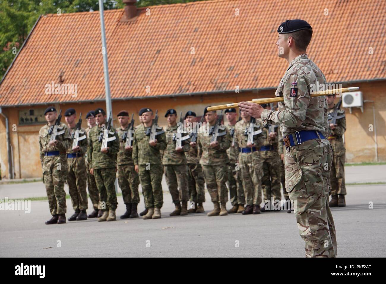 Cpl. Thomas Warner, Senior Instructor for the Potential Non-Commissioned Officer's (PNCO) Candidate Course, Queen's Dragoon Guard, British Armed Forces, leads a multinational formation at their graduation ceremony at the Bemowo Piskie Training Area, Poland, August 3, 2018. The graduation ceremony marks the conclusion of a two week course that tested the junior Soldiers' mental and physical capabilities. Stock Photo