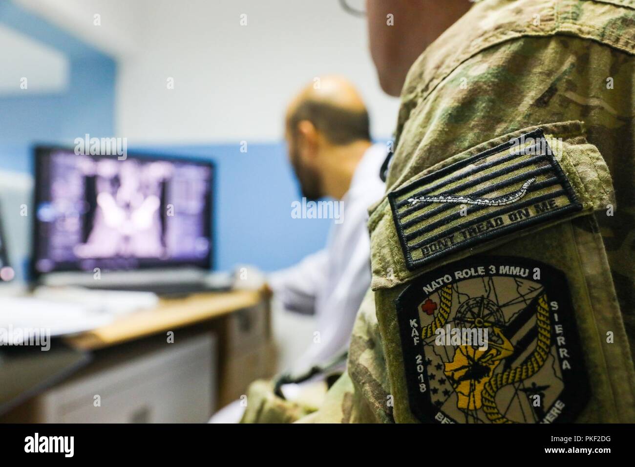 KANDAHAR PROVINCE, Afghanistan (August 5, 2018) -- U.S. Navy Lt. Cdr. Justin S. Clark, radiology technician for Kandahar Airfield NATO Role III Multinational Medical Unit, watches as his Afghan radiology counterpart checks the results of an x-ray, August 5, 2018, during a medical advisory visit at Kandahar Regional Military Hospital, Camp Hero in Kandahar, Afghanistan. Staff members from the Role III conduct routine visits to KRMH to train and advice Afghan medical staff. Stock Photo