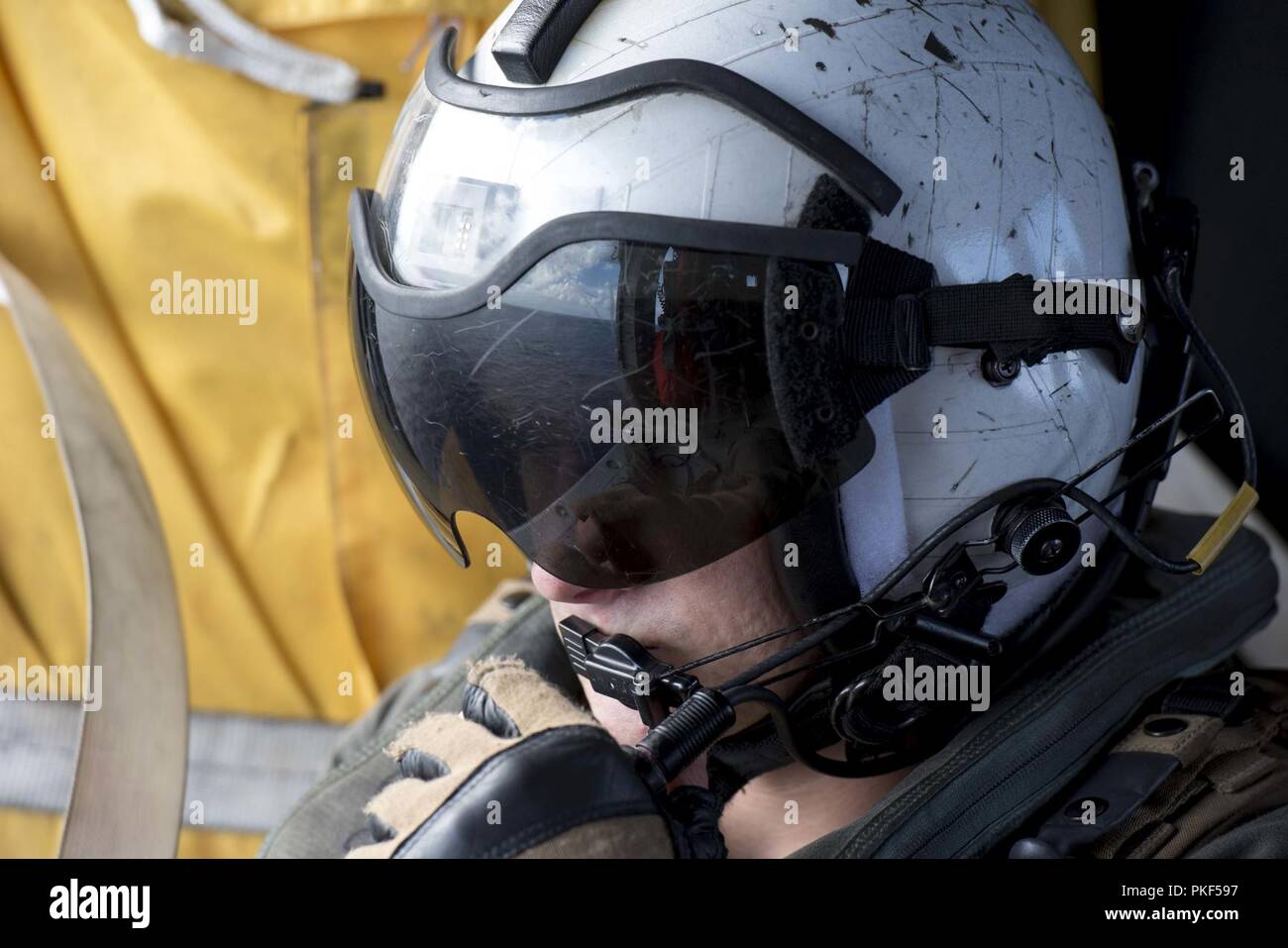 ATLANTIC OCEAN (Aug 4, 2018) Naval Air Crewman (Helicopter) 2rd Class Loren Mills, from Satellite Beach, Florida, looks out the door of an MH-60S Sea Hawk, which is attached to Helicopter Sea Combat Squadron 9, embarked aboard the aircraft carrier USS George H.W. Bush (CVN 77). The ship is underway conducting routine training exercises to maintain carrier readiness. Stock Photo