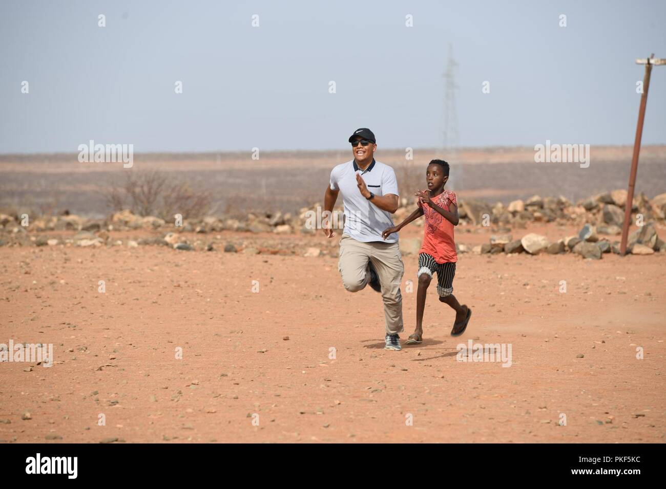 U.S. Air Force 1st Lt. Darren Domingo, a Combat Camera officer deployed to Combined Joint Task Force - Horn of Africa, races with local children at a soccer field in Chabelley, Djibouti, Aug. 3, 2018. Community relations events give service members the opportunity to build relationships and contribute to local communities. Stock Photo