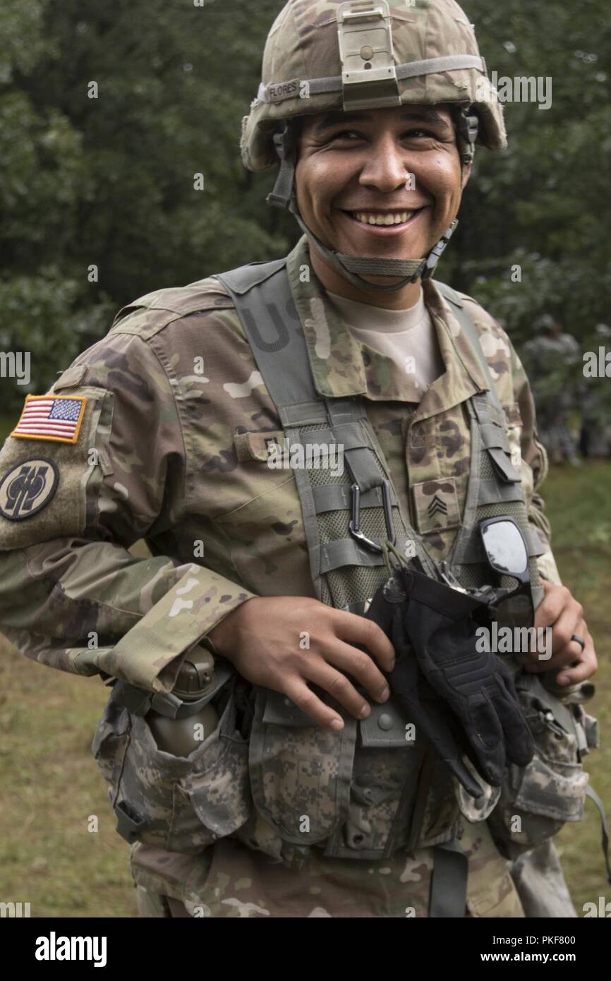 Sgt. Raul Flores, a U.S. Army Reserve military police Soldier assigned to the 324th Military Police Company, poses for a photo between lethal warrior skills training lanes as part of Operation Blue Shield Aug. 7, 2018 at Fort McCoy, Wisconsin. Operation Blue Shield is a functional exercise, broken down into 2-week cycles, centered on squad and team-level training with a focus on internment, resettlement, detainee operations and combat support. During each two-week cycle, Solders train on internment operations, weapons qualification, biometrics, reflexive fire, and Military Operations on Urbani Stock Photo