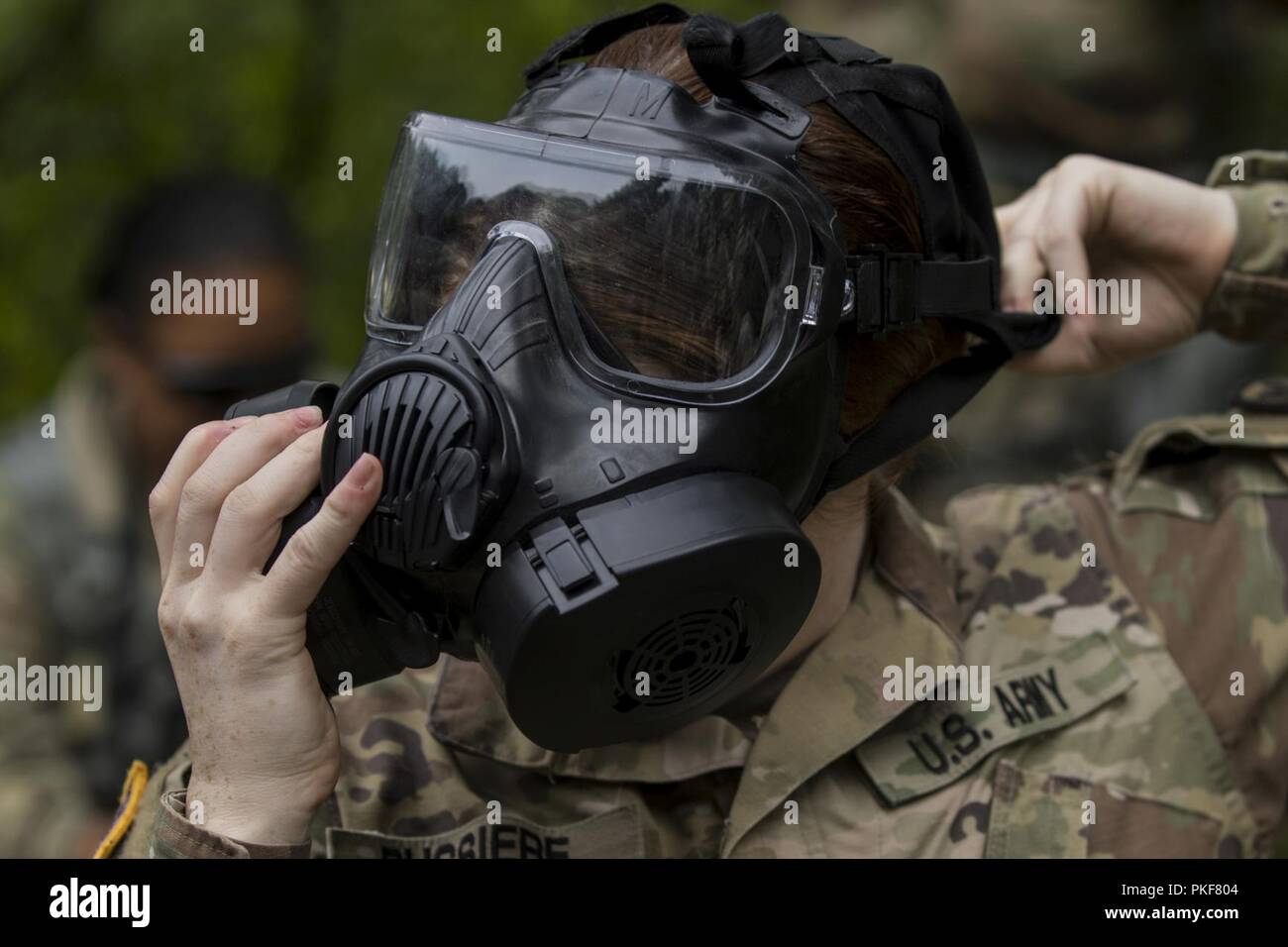 Pfc. Taylor Bussiere, an Army Reserve military police Soldier assigned to the 302nd Military Police Company based out of Grand Prairie, Texas, dons her protective mask during a simulated chemical attack during lethal warrior skills training as part of Operation Blue Shield Aug. 7, 2018, at Fort McCoy, Wisconsin. Operation Blue Shield, is a functional exercise, broken down into 2-week cycles, centered on squad and team-level training with a focus on internment, resettlement, detainee operations and combat support. During each two-week cycle, Solders train on internment operations, weapons quali Stock Photo