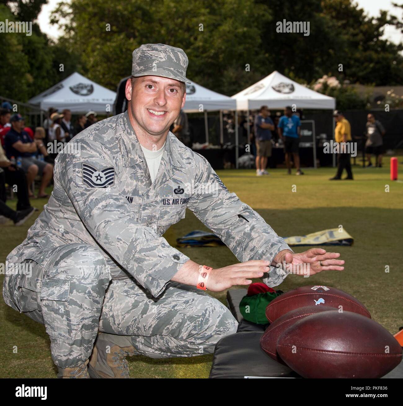 U.S. Air Force Tech. Sgt. James Hodgman, 60th Air Mobility Wing, poses with footballs during Oakland Raiders training camp in Napa Valley, Calif., August 7, 2018. Travis Airmen were treated to a scrimmage between the Raiders and Detroit Lions and a meet and greet autograph session with players and coaches from both teams. Stock Photo