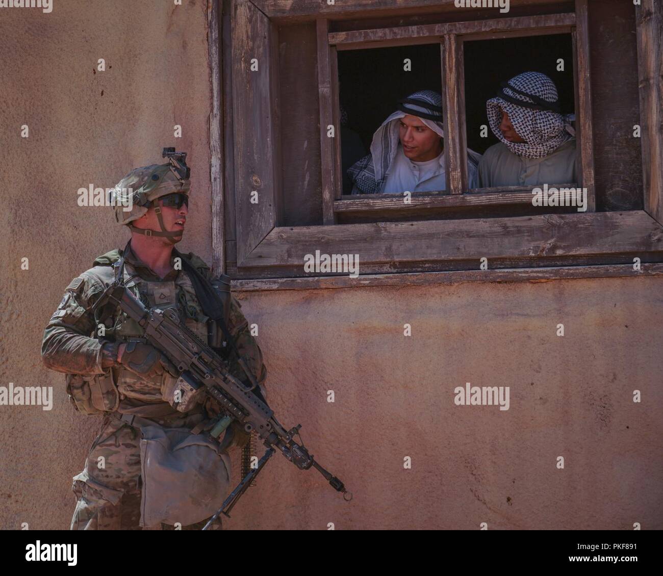 A Soldier with Company A, 3rd Battalion, 41st Cavalry Regiment, 1st Stryker Brigade Combat Team, 1st Armored Division communicates with the locals at the mock city, Palmiyah, during the unit's assault on the objective, Aug. 5 at Orogrande, New Mexico.     Iron Focus is a one of the largest exercises conducted on Fort Bliss and surrounding areas as part of the 1st Armored Division Commander's Combat Training Center Certification program. Every echelon of the Brigade is challenged through their ability to conduct offensive, defensive and stability operations against a hybrid threat, as well as b Stock Photo