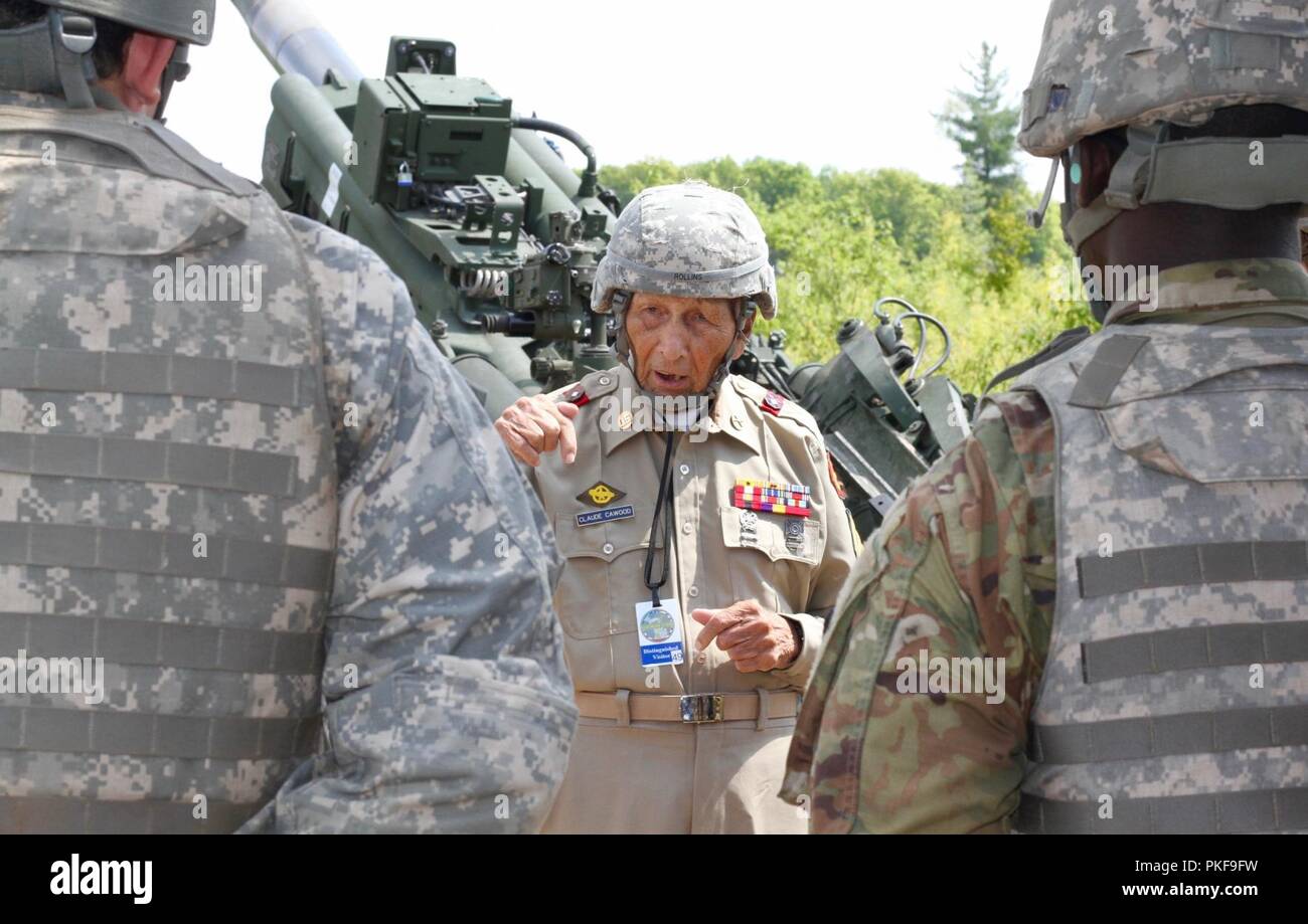 CAMP GRAYLING, Mich. - World War II veteran, Claude Cawood, talks with Rhode Island Army National Guard Soldiers from Battery A, 1st Battalion, 103rd Field Artillery Regiment, during a visit to the Northern Strike exercise on Aug. 9, 2018 at Camp Grayling, Mich. Cawood, a former section chief on the M105 Howitzer during his three years in the Philippines had an opportunity to visit Soldiers and fire an M777 Howitzer. Stock Photo