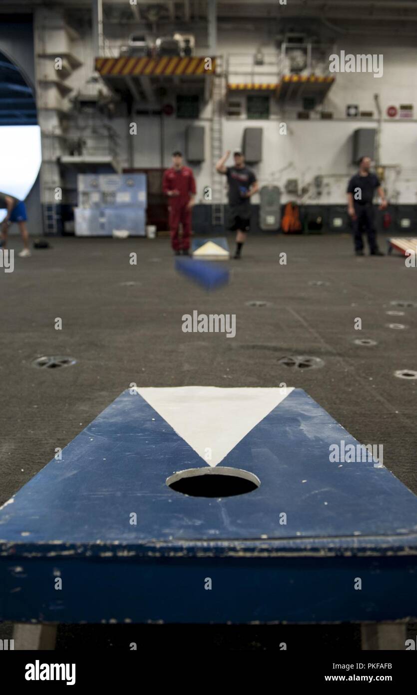 ATLANTIC OCEAN (Aug. 7, 2018) Damage Controlman 3rd Class Trevor Jolicoeur, left, from Chippewafalls, Wisconsin, and Hull Maintenance Technician 3rd Class Woodrow Baker, from Temecula, California, participate in a Morale, Welfare and Recreation sponsored cornhole tournament aboard the aircraft carrier USS George H.W. Bush (CVN 77). The ship is underway conducting routine training exercises to maintain carrier readiness. Stock Photo
