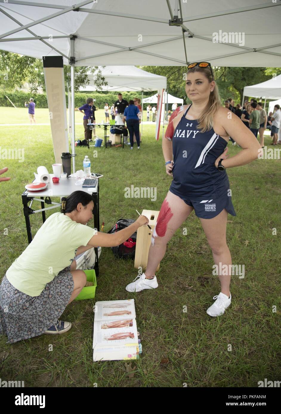 A medical illustrator applies body paint to Navy Intelligence Specialist  Cassidy Busch during the National Museum of Health and Medicine's (NMHM)  annual Anatomy of Sports program at the NMHM in Silver Spring