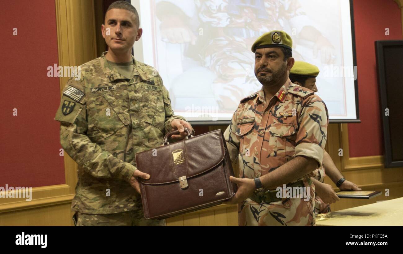 U.S. Army Maj. Jared Siverling, a liaison for the 157th Military Engagement Team, attached to U.S. Army Central, accepts a gift from Royal Army of Oman Col. Said Hamood Al-Jabri at a ceremony held to celebrate a successful engagement between the two military forces in Haima, Oman, Aug. 9, 2018. The engagement focused on sharing best practices and techniques for increasing border security, and also created an opportunity for U.S. Army Soldiers to build relationships with partner nation forces. Stock Photo