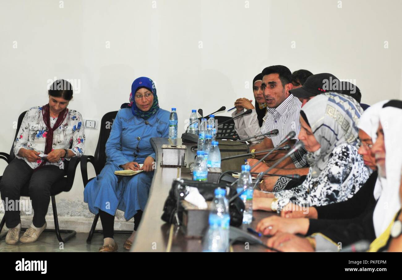 A chairperson for the Social Services Committee of the Civil Administration of Manbij discusses plans for dealing with return of residents displaced during ISIS occupation at a meeting at the CAM headquarters in Manbij, Syria, August 9, 2018. People have been returning home to Manbij now that the city is safe and secure since the SDF liberated the area from ISIS in 2016. Stock Photo