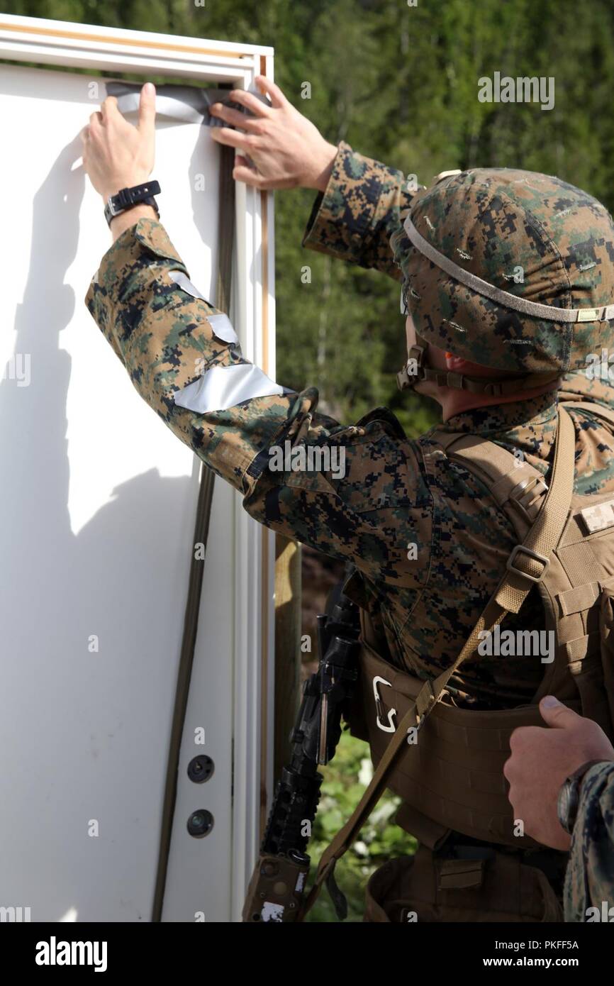 A U.S. Marine with Marine Rotational Force-Europe 18.1 attaches a detonation cord linear charge to a door during an urban breaching range at Giskas, Norway, Aug. 8, 2018. The range gave Marines the opportunity to clear a shoot house with several obstacles including a gate, doors, and walls. The Marines worked in squads to construct different explosive charges and breach various barriers. Stock Photo