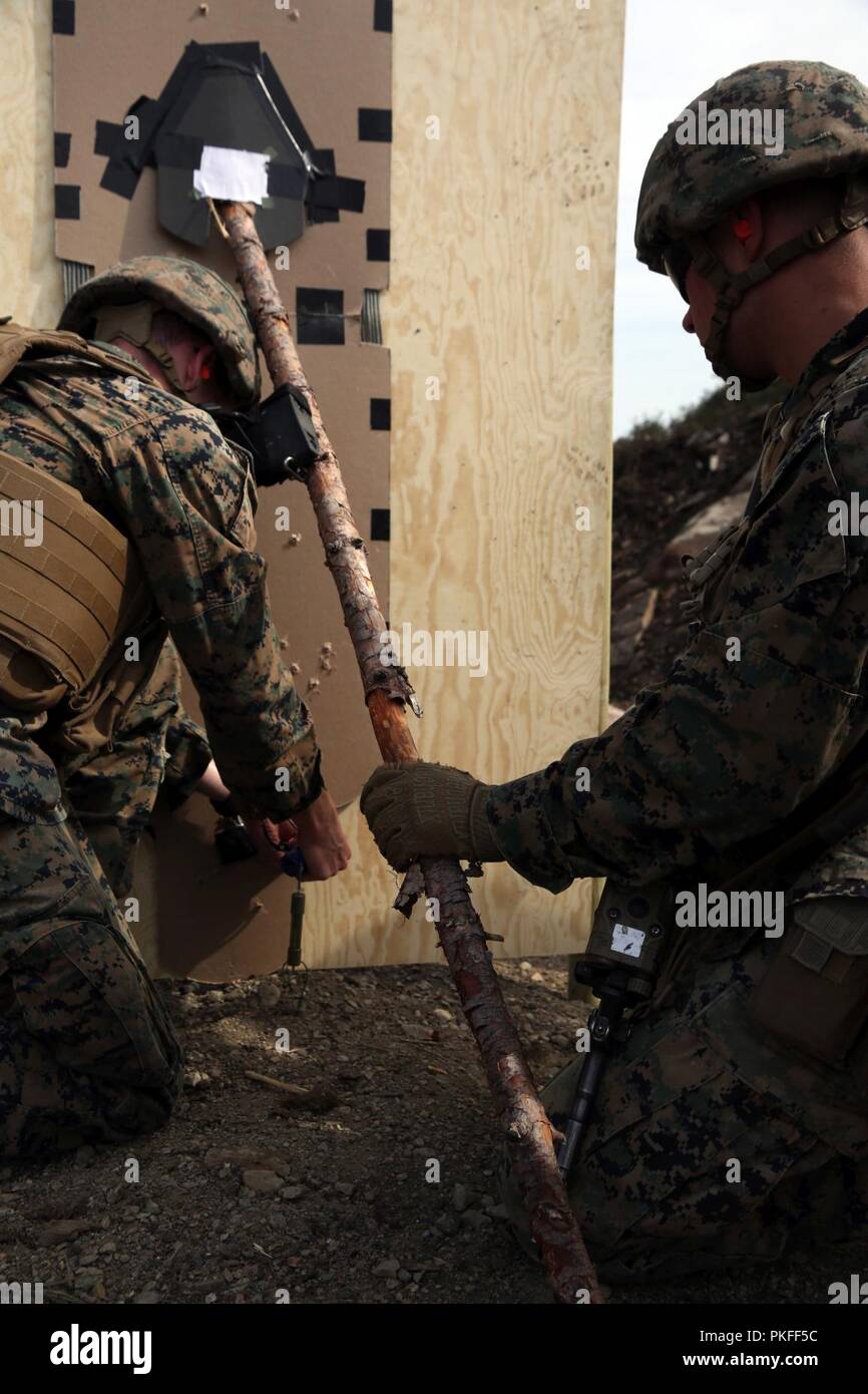 U.S. Marines with Marine Rotational Force-Europe 18.1 set up an oval charge to a barricade during an urban breaching range at Giskas, Norway, Aug. 8, 2018. The range gave Marines the opportunity to clear a shoot house with several obstacles including a gate, doors, and walls. The Marines worked in squads to construct different explosive charges and breach various barriers. Stock Photo