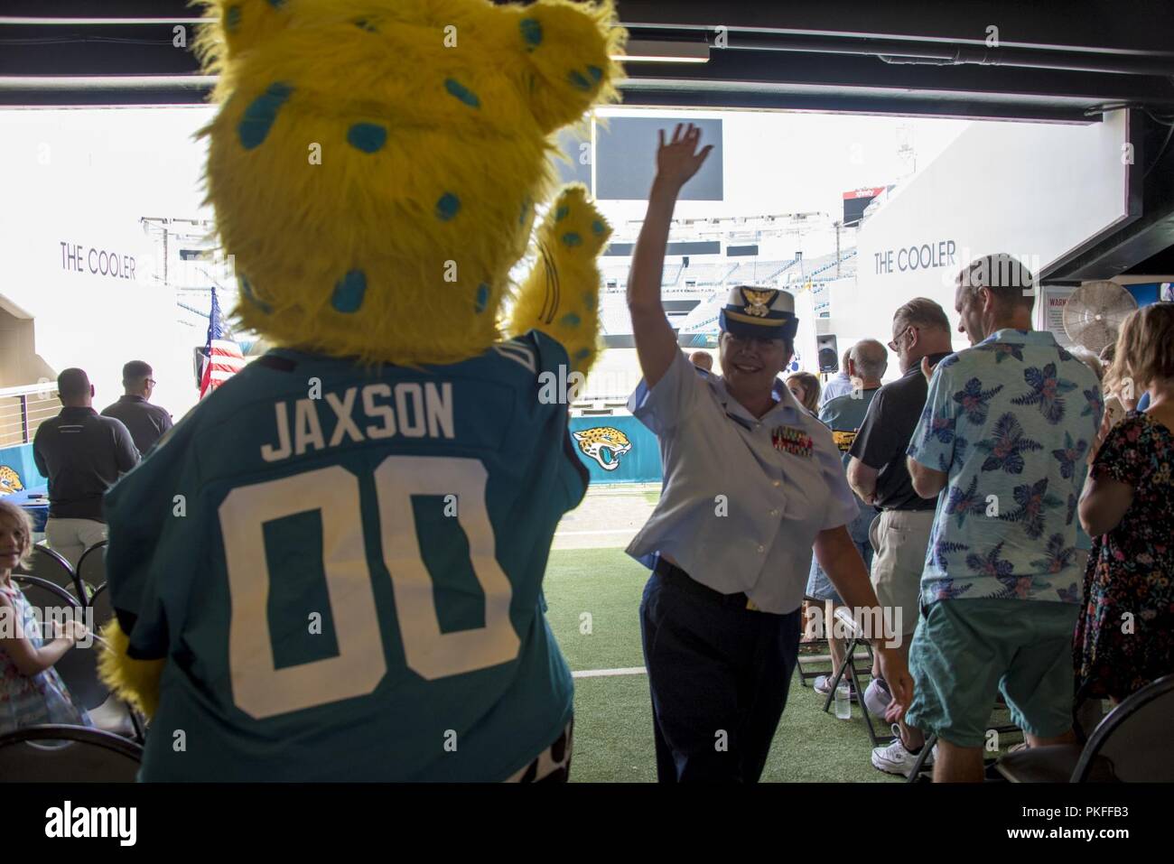 Reserve Chief Warrant Officer Faith Matuschek walks down the aisle and high fives Jaxson de Ville, the Jacksonville Jaguars mascot, after officially retiring August 10, 2018, during her retirement ceremony at TIAA Bank Field in Jacksonville, Florida. Matuschek retired after 23 years of military service in the U.S. Navy and U.S. Coast Guard. Stock Photo