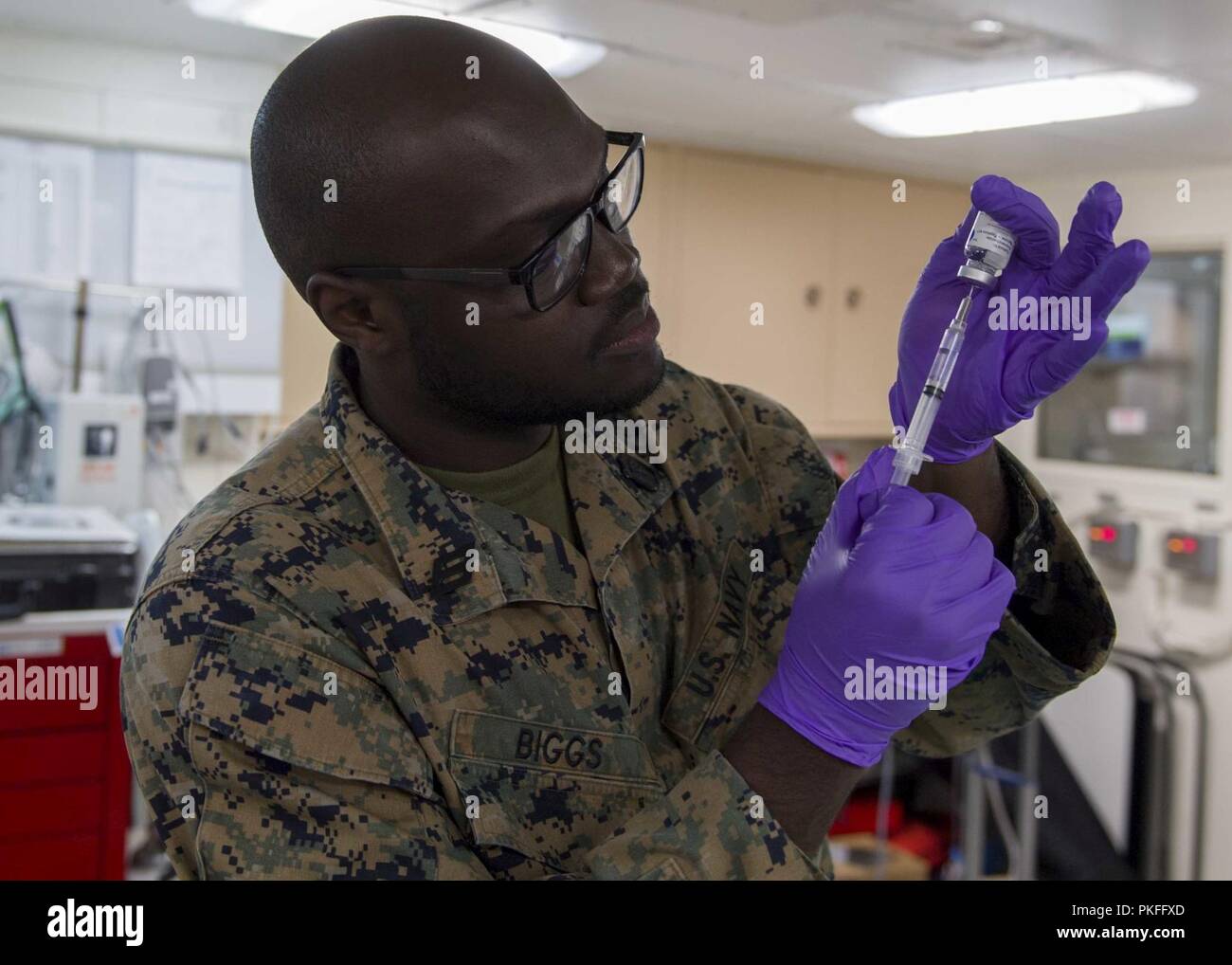 PACIFIC OCEAN (July 26, 2018) Hospitalman Javaugh Biggs, from St. Andrew, Jamaica, assigned to Battalion Landing Team 3/1, prepares a medical syringe in the medical ward of San Antonio-class amphibious transport dock USS Anchorage (LPD 23) during a regularly scheduled deployment of Essex Amphibious Ready Group (ARG) and 13th Marine Expeditionary Unit (MEU). The Essex ARG/MEU team is a strong and flexible force equipped and scalable to respond to any crisis ranging from humanitarian assistance and disaster relief to contingency operations. Stock Photo