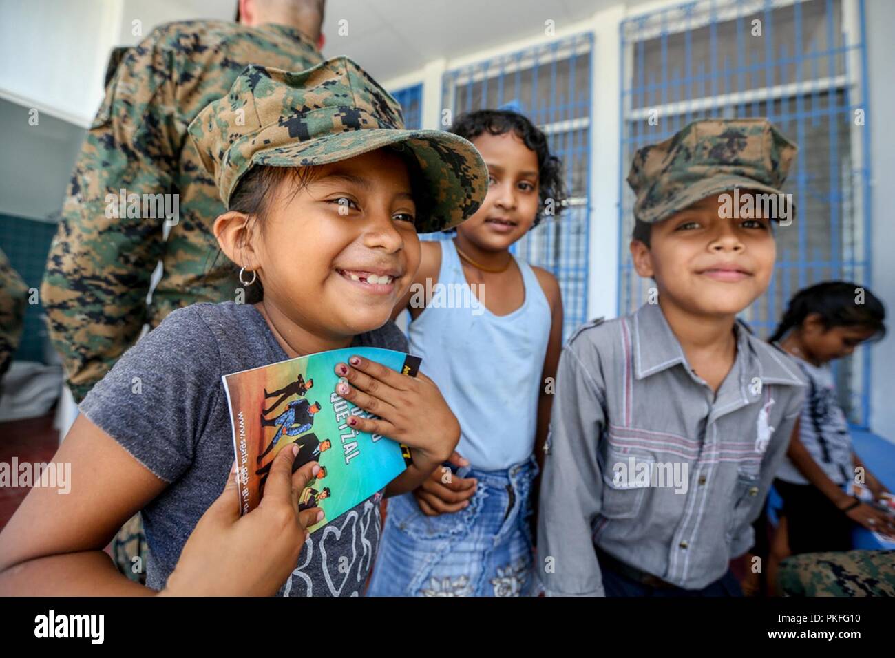 Guatemalan children smile and hold booklets given to them by Guatemalan Army engineers in La Paz, Guatemala, Aug. 6, 2018 . The Marines and sailors of SPMAGTF-SC are conducting security cooperation training and engineering projects alongside partner nation military forces in Central and South America. The unit is also on standby to provide humanitarian assistance and disaster relief in the event of a hurricane or other emergency in the region. Stock Photo