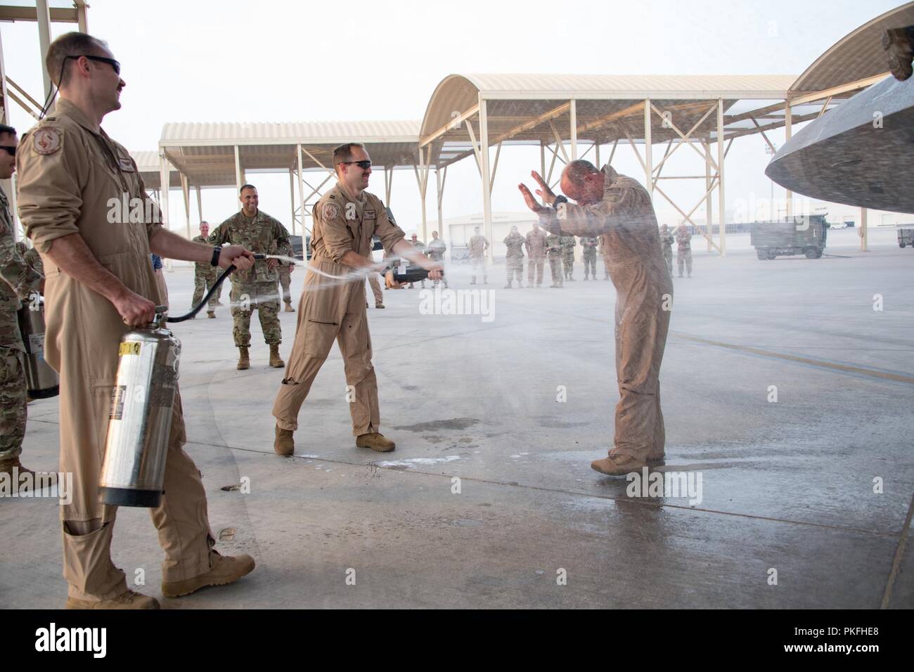 U.S. Air Force Lt. Gen. Jeffrey L. Harrigian, Commander U.S. Air Forces Central Command, is ceremoniously doused in water by Airmen as he exits an F-22 commemorating his final flight, or “fini flight,” at Al Dhafra Air Base, August 8, 2018. The general took command of AFCENT in July 2016, and has flown multiple missions in the F-22 Raptor as part of Operation Inherent Resolve in Iraq and Syria. Stock Photo