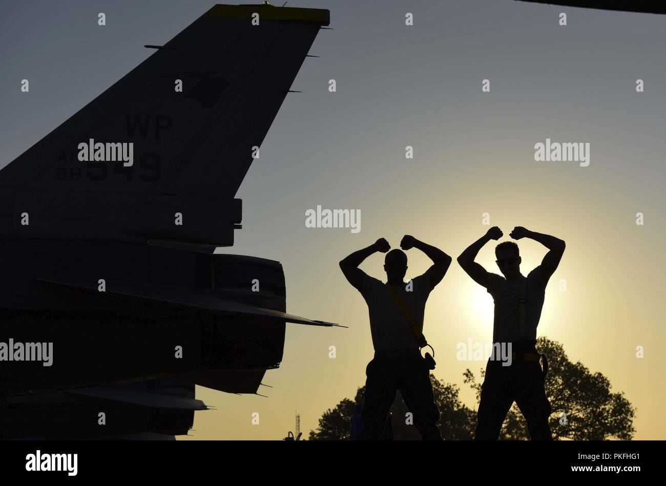 U.S. Air Force Senior Airman Robert Brooks (left), and Senior Airman Nathaniel Lott (right), 80th Aircraft Maintenance Unit crew chiefs, stand next to an F-16 Fighting Falcon in their unit’s iconic “Crush ‘Em” stance during Exercise Pitch Black 2018 at Royal Australian Air Force Base Darwin, Australia, Aug. 9, 2018. This exercise allows U.S. Pacific Air Forces Airmen and the Royal Australian Air Force to train together and increase interoperability with air and ground forces from within the Indo-Pacific region. Stock Photo