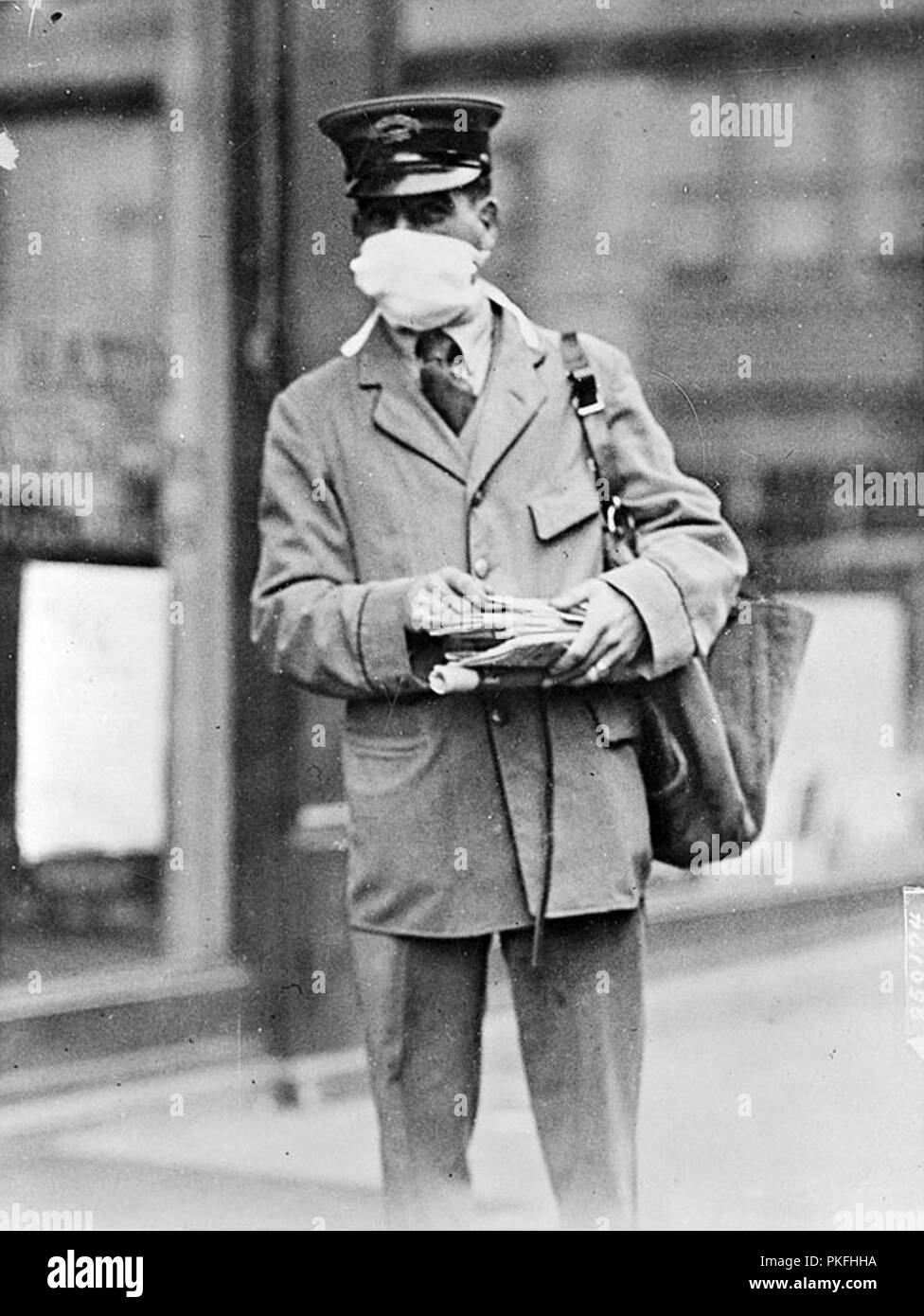 A New York City mailman goes about his business while wearing a gauze mask designed to stop infection during the fall of 1918. U.S. Army units mobilizing for World War I were struck hard by the virus which often hit military bases first and then spread to civilians. Camp Upton on Long Island was closed to visitors in the fall of 1918 to prevent the spread of the flu. Stock Photo