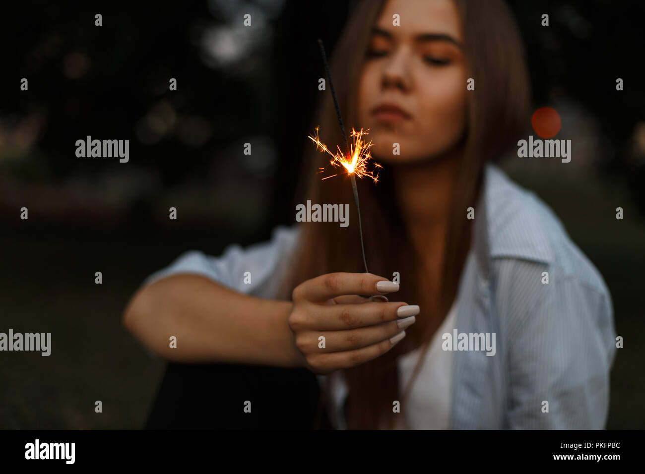 Beautiful burning Bengali fire with sparks in female hands Stock Photo