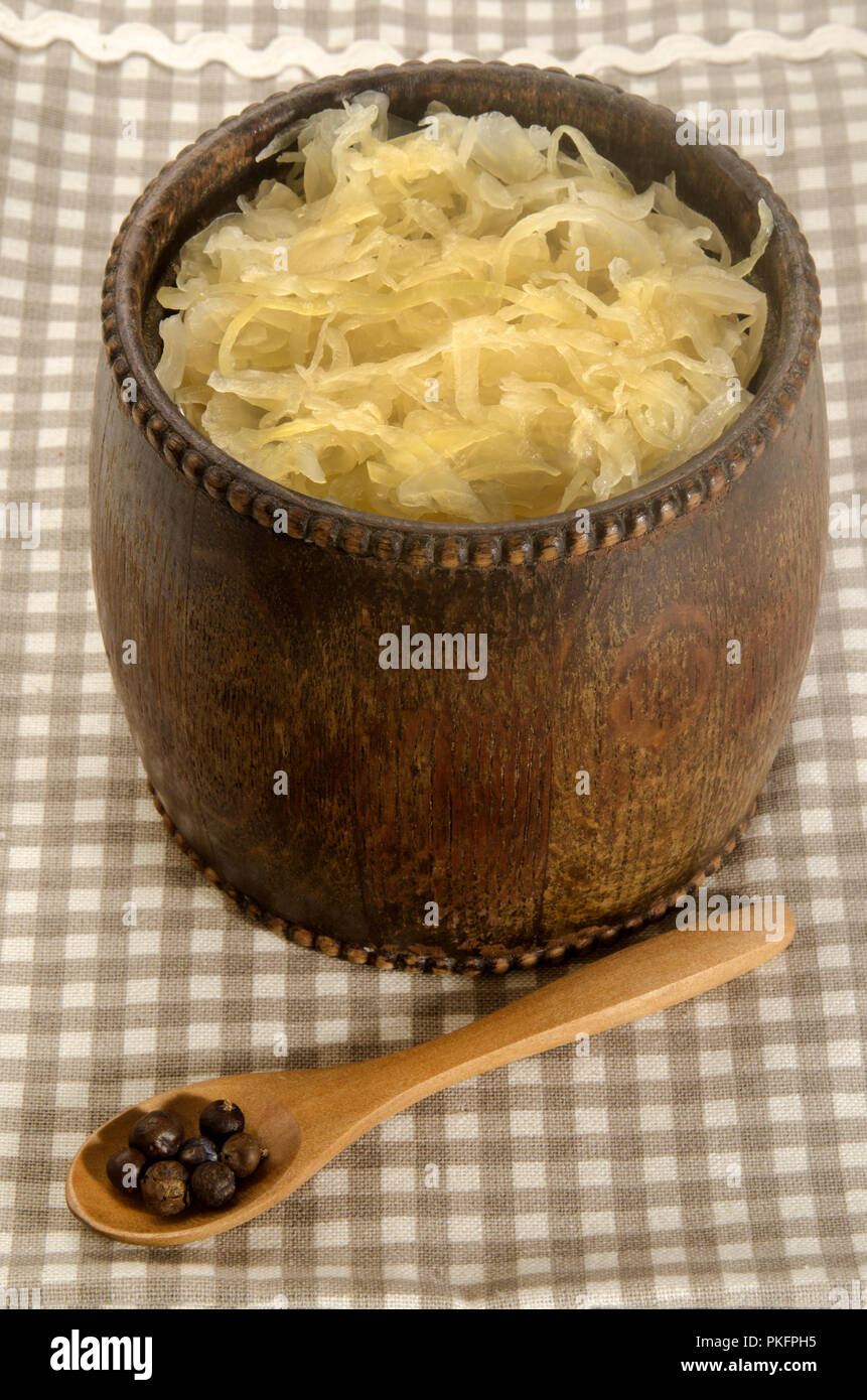 home made fresh sauerkraut in a wood barrel and spoon with juniper